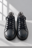 Sneakers in pelle scura su sfondo grigio.png
